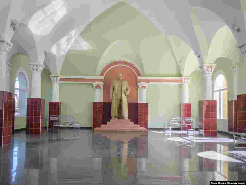 Statuia lui Stalin din gara orașului Gori. Statuia este amplasată într-o sală de așteptare, aparent nefolosită. Fotografia a fost făcută în septembrie 2022, pe fereastra ușii încuiate.(Foto: Amos Chapple, RFE/RL)