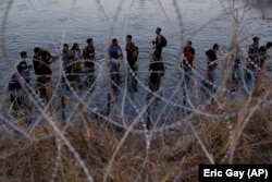 Migrantlar Meksikadan ABŞ-a aşmak üçin, tikenli germewden geçmek mümkinçiligine garaşýarlar.