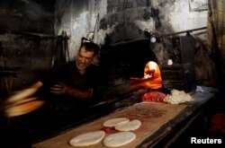 Un brutar palestinian coace pâine pe lemne de foc, pe fondul lipsei de combustibil și de energie electrică, în Khan Younis, sudul Fâșiei Gaza, 16 octombrie 2023.
