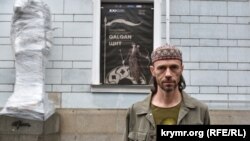 Рустем Скибін біля Київської картинної галереї перед відкриттям виставки, про яку повідомляє оголошення на стіні будівлі