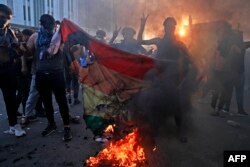 Susținători ai mișcării irakiene Sadrist ard un steag curcubeu în fața ambasadei suedeze din Bagdad, la 30 iunie 2023, în cea de-a doua zi de proteste împotriva arderii Coranului în fața unei moschei din Stockholm, care i-a indignat pe musulmanii din întreaga lume.
