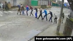Кадр камеры видеонаблюдения. Российские военные ведут девять человек под прицелами автоматов. Впоследствие эти люди найдены убитыми