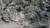 Câțiva palestinieni se uită la clădirea distrusă în urma unui atac aerian israelian în tabăra Nuseirat din centrul Fâșiei Gaza, luni, 16 octombrie 2023.