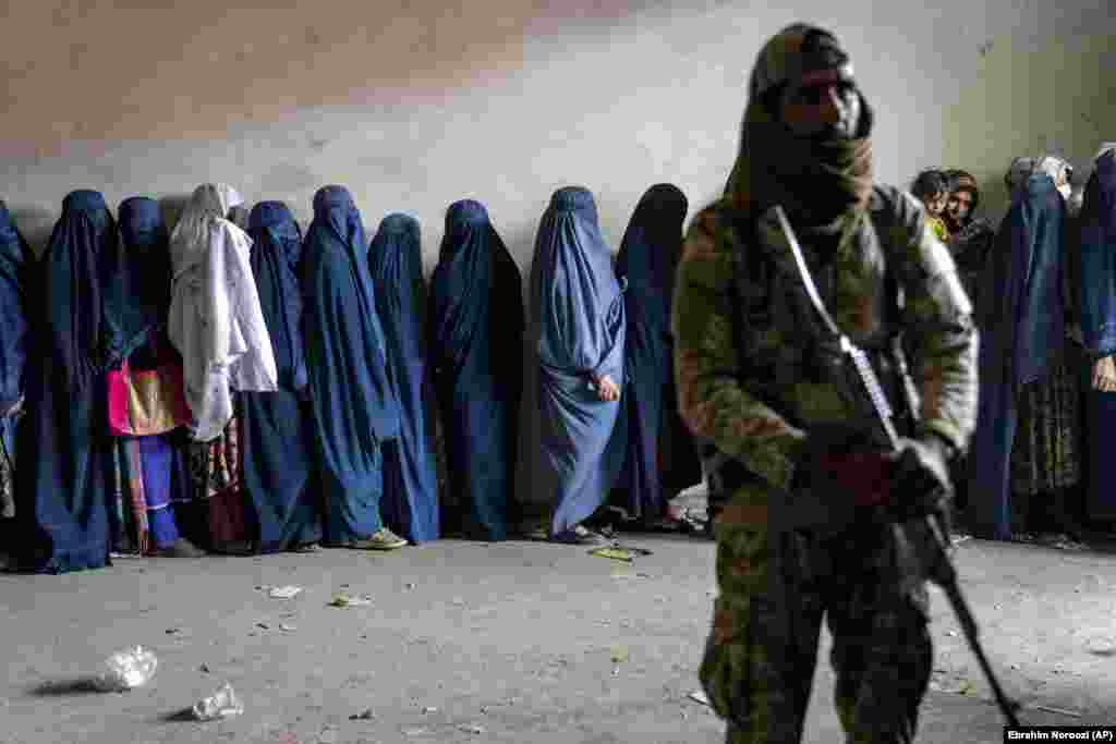 Talyban söweşijisi, ynsanperwer kömek topary tarapyndan paýlanan azyk önümlerini almak üçin garaşýan zenanlara garawullyk edýär, Kabul, Owganystan, 23-nji maý, 2023.&nbsp;&nbsp;(AP suraty/Ebrahim Noroozi)
