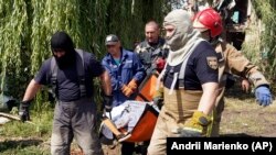 Spasioci nose tijelo žene ubijene u ruskom raketnom napadu u Čuhuivu, u ukrajinskoj oblasti Harkov, 26. juli 2022.