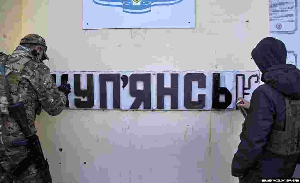 Український військовий та вуличний художник змінюють напис на табличці з російської мови на українську &nbsp;