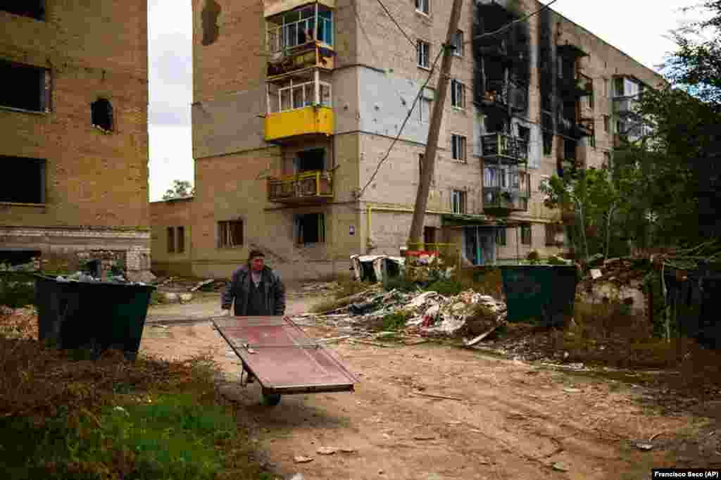62-річний Микола везе на тачці двері, щоб відремонтувати свій будинок. Люди, як можуть, готуються до наближення зими. У місті досі немає ні світла, ні газу. Ізюм, Харківська область, 3 жовтня 2022 року. Чимало літніх людей залишилися у своїх домівках, незважаючи на те, що український уряд закликав їх переїхати у безпечніші місця. Можливість евакуюватися у жителів Ізюму була лише у березні, до того як місто захопила російська армія. 