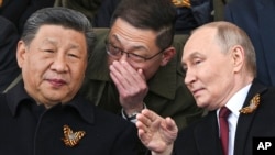 Russian President Vladimir Putin and Chinese leader Xi Jinping talk as they watch the Victory Day military parade in Moscow in May 2025. 