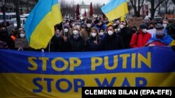 Демонстранты держат транспарант с надписью: «Остановите Путина, остановите войну» – во время митинга перед посольством России в Берлине. Германия, 22 февраля 2022 года 