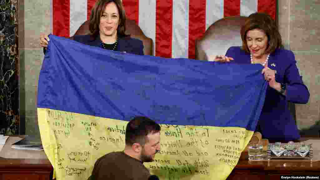 Harris és Nancy Pelosi, az amerikai képviselőház elnöke tartja a feliratos ukrán zászlót, amelyet Volodimir Zelenszkij ukrán elnök hozott Bahmutból az amerikai kongresszus ülésén mondott beszédére 2022. december 21-én. „Bahmut kitart – mondta Zelenszkij éljenzés közepette. – Ukrajna tartja a frontot, és soha nem adja fel” – tette hozzá