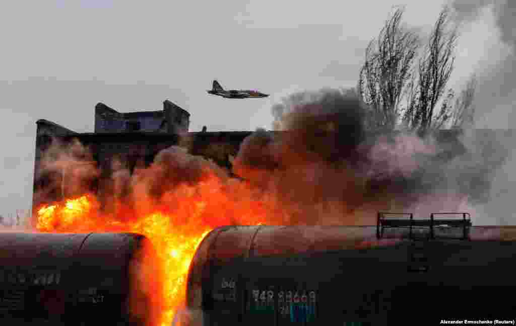 Un avion de luptă rusesc zboară deasupra unui nod de cale ferată în flăcări în urma bombardamentelor recente în orașul Șahtarsk, în apropiere de Donețk, în Ucraina controlată de Rusia.