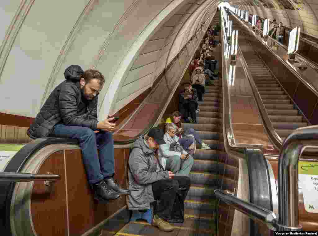 Locuitori ai Kievului adăpostându-se pe scara rulantă a unei stații de metrou în timpul unui atac cu rachete rusești asupra capitalei ucrainene.