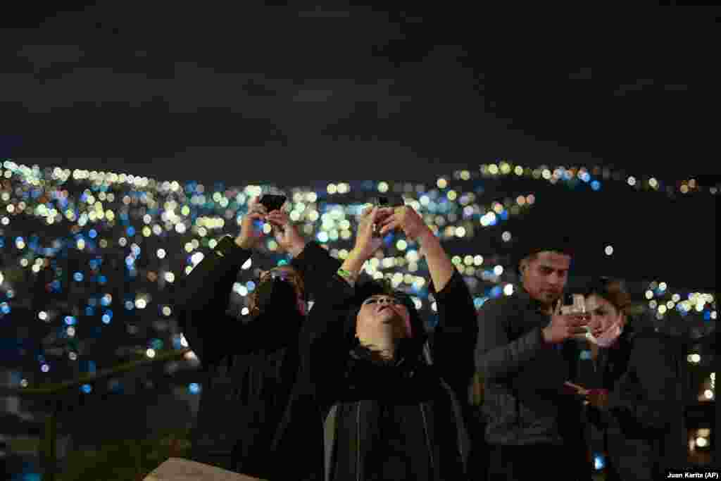 Oamenii fotografiază eclipsa în La Paz, Bolivia, 15 mai 2022.&nbsp;Vizibil cu ochiul liber sau cu ajutorul unui binoclu, fenomenul poate oferi celor pasionaţi posibilitatea de a face &bdquo;fotografii spectaculoase&quot;, atunci când condiţiile atmosferice sunt favorabile.&nbsp;