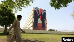 A man walks past a giant portrait of Pakistani Prime Minister Nawaz Sharif (L) and Chinese President Xi Jinping displayed on a building in Islamabad, April 21.