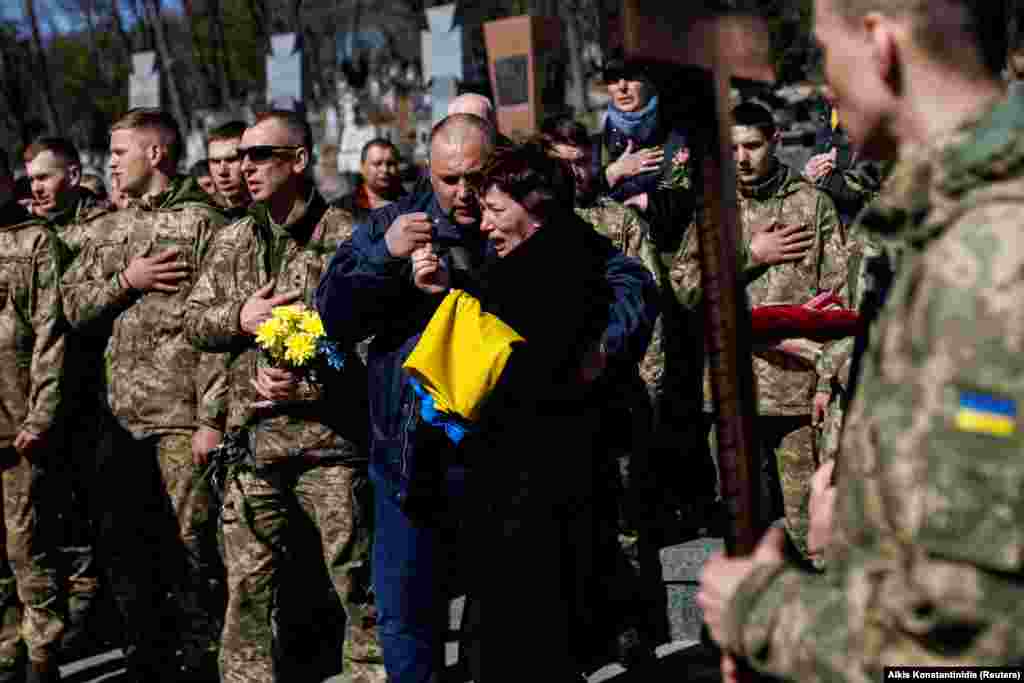 Mama locotenentului ucrainean Pavlo Cernikov plânge la funeraliile acestuia în timp de soldații intonează imnul național al Ucrainei în cimitirul Leakiv cemetery, Liov, 28 martie 2022.