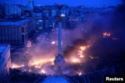Fumul se ridică deasupra Pieței Independenței în timpul protestelor antiguvernamentale din centrul Kievului, la primele ore ale zilei de 19 februarie 2014.