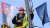Serbia -- A worker arranges flags of Serbia and EU on a lamppost in Belgrade, 02Mar2012