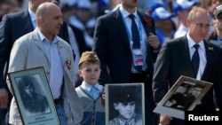 Orsýetiň prezidenti Wladimir Putin (s) öz kakasynyň portreti bilen, Moskwa, 9-njy maý, 2015. 