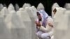 Боснийские мусульманки молятся у могил своих родственников на мемориальном кладбище в Сребренице