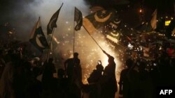 Pakistanis wave the national flag as they celebrate the cease-fire between Pakistan and India, in Hyderabad, Sindh Province, on May 10.