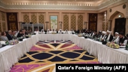 FILE: Qatari officials (C) take part in meeting between U.S. special envoy Zalmay Khalilzad (2nd-L), and the U.S. delegation, and Sher Mohammad Abbas Stanikzai (6th-R), and the Taliban delegation in Doha on February 26.