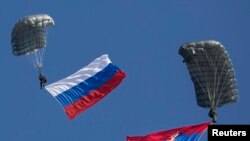 Serbian paratroopers descend to the ground holding Serbian and Russian (L) national flags during a training exercise in the village of Nikinci, west from Belgrade, November 14, 2014