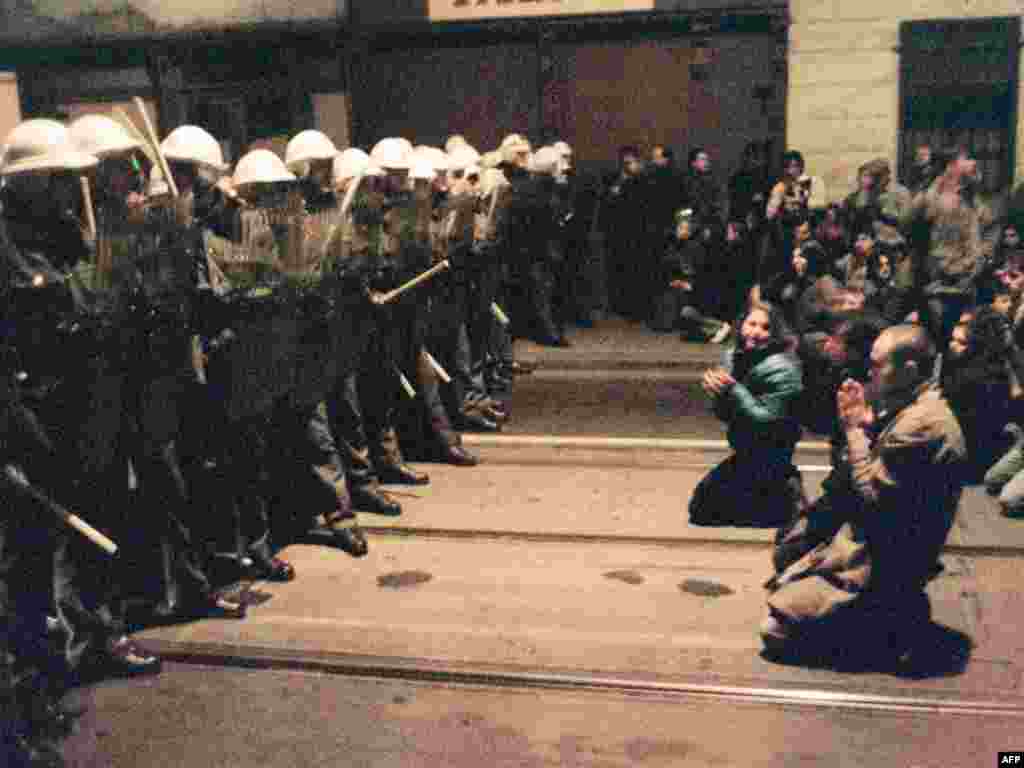 19-njy noýabrda alnan bu suratda protestçiler Pragada polisiýa bilen ýüzbe-ýüz bolan pursatynda dyzyna çökýärler. Polisiýa ýene-de zor görkezmek bilen jogap berdi.