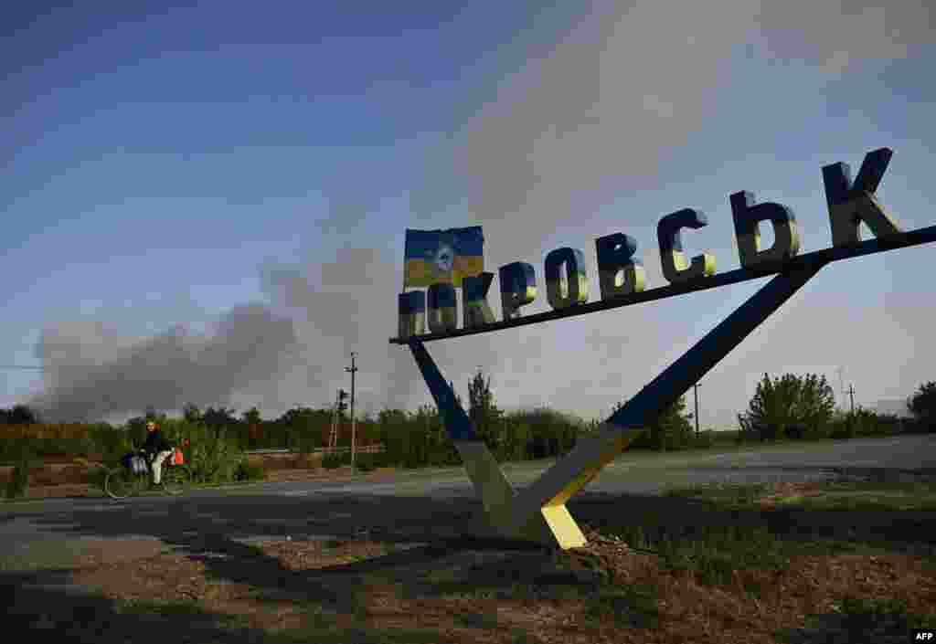 Велосипедист проезжает мимо указателя на въезде в Покровск, сентябрь 2024 года. С июля российские войска продвигаются к Покровску. До войны в городе проживало около 60 тысяч человек. Покровск называют западными воротами Донбасса 