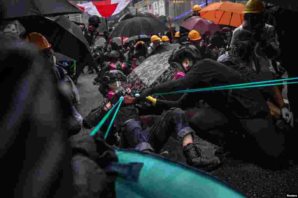 Митингчилер атайын бөлүктүн кызматкерлерине каршы желим ача (рогатка) колдонууда. 25-август, 2019-жыл. 