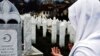 Боснійська мусульманка молиться за свого родича, похованого на військовому цвинтарі в Сараєво, 2007 рік
