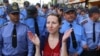 A Belarusian woman applauds in front of a police line as part of a creative antiregime protest, one of many to have taken place in the country in recent weeks.