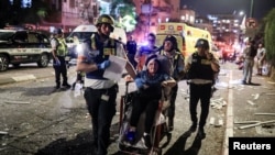 Spasilačke ekipe pomažu ženi povrijeđenoj u iranskom raketnom napadu, u Ramat Ganu, 13. juna