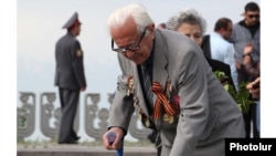 Armenia -- An elderly veteran lays flowers at a World War Two memorial in Yerevan, 9 May 2010.