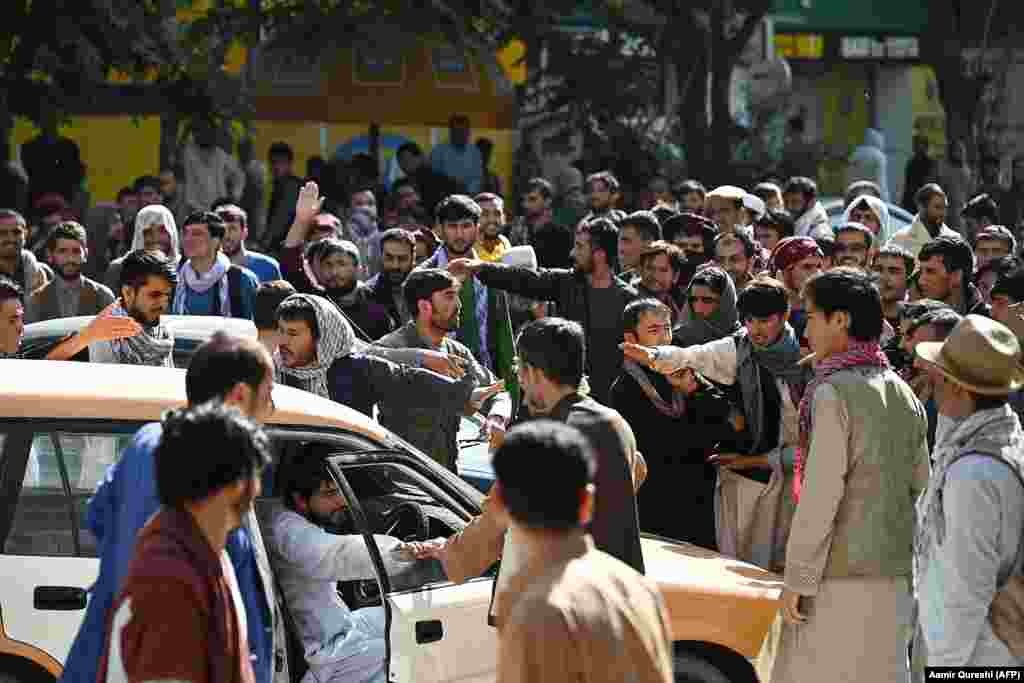 O mulțime de oameni în fața sucursalei închise a unei bănci din Kabul la 28 august. De când au preluat talibanii puterea în Kabul, multe clădiri guvernamentale, bănci, școli și universități au fost închise. Pe măsură ce prețurile cresc, sunt tot mai puțini bani lichizi pe piață. 