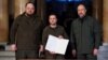 Президент України Володимир Зеленський (посередині) під час підписання заявки на членство України в Євросоюзі. Поряд із ним голова Верховної Ради Руслан Стефанчук (ліворуч) і прем'єр-міністр України Денис Шмигаль (праворуч). Київ, 28 лютого 2022 року
