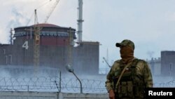 Vojnik s ruskom zastavom na uniformi čuva stražu u blizini nuklearne elektrane Zaporižja, avgust 2022.