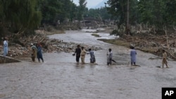 Buner rayonundakı Pişoren kəndində daşqından sonra yerli sakinlər çayı keçirlər.