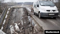 Автомобіль переїздить зруйнований війною міст в Луганській області, березень, 2015 року