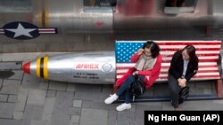 Китаянки перед магазином одежды на скамейке с флагом США, Пекин, 23 марта 2018