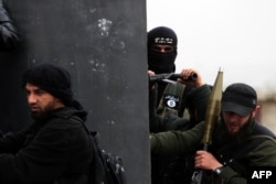 یک جنگجوی تُرک از گروه جهادی «جبهه‌النصره» با پرچم القاعده روی کاپشن خود در کنار دیگر نیروهای جهادی در سوریه، فروردین ۱۳۹۲