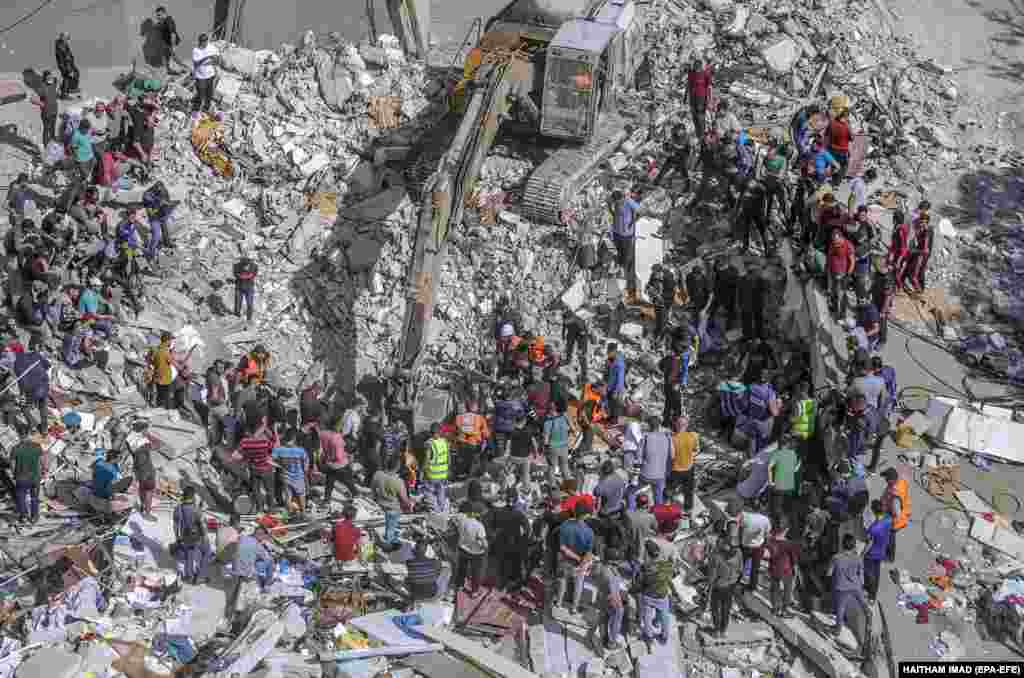 Protecția civilă palestiniană caută supraviețuitori în ruinele unei case distruse după un atac aerian israelian asupra orașului Gaza, 16 mai 2021. Atacurile aeriene israeliene au distrus reședința liderului Hamas în Fâșia Gaza împreună cu alte două clădiri în 16 mai, ucigând cel puțin 42 de persoane - cel mai ucigător atac unic de când s-au declanșat luptele între Israel și guvernanții Hamas din Gaza, în urmă cu aproape o săptămână.