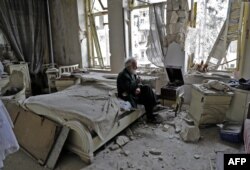 Sedamdesetogodišnjak puši lulu i sluša muziku na gramofonu u spavaćoj sobi svog devastiranog doma, Alep, 9. mart 2017. Foto: Joseph Eid/AFP