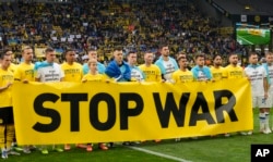 Jucătorii Borussiei Dortmund și echipei ucrainene Dinamo Kiev înaintea unui meci din Liga Campionilor din aprilie 2022, pe stadionul din orașul german, cu mesajul „Opriți războiul”.