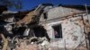 Село Пески: женщина смотрит в окно дома, разрушенного в результате обстрелов