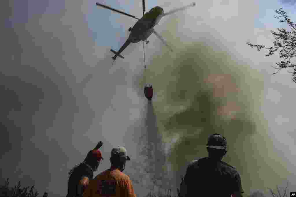 Një helikopter duke hedhur ujë mbi fshatin Sirtkoi, të shkrumbuar nga zjarri, afër Manavgatit, në Antalia. (1 gusht)