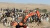 Un excavator sapă printre ruinele unei case preăbușite în districtul Zenda Jan din provincia Herat, din vestul Afganistanului, duminică, 8 octombrie 2023.