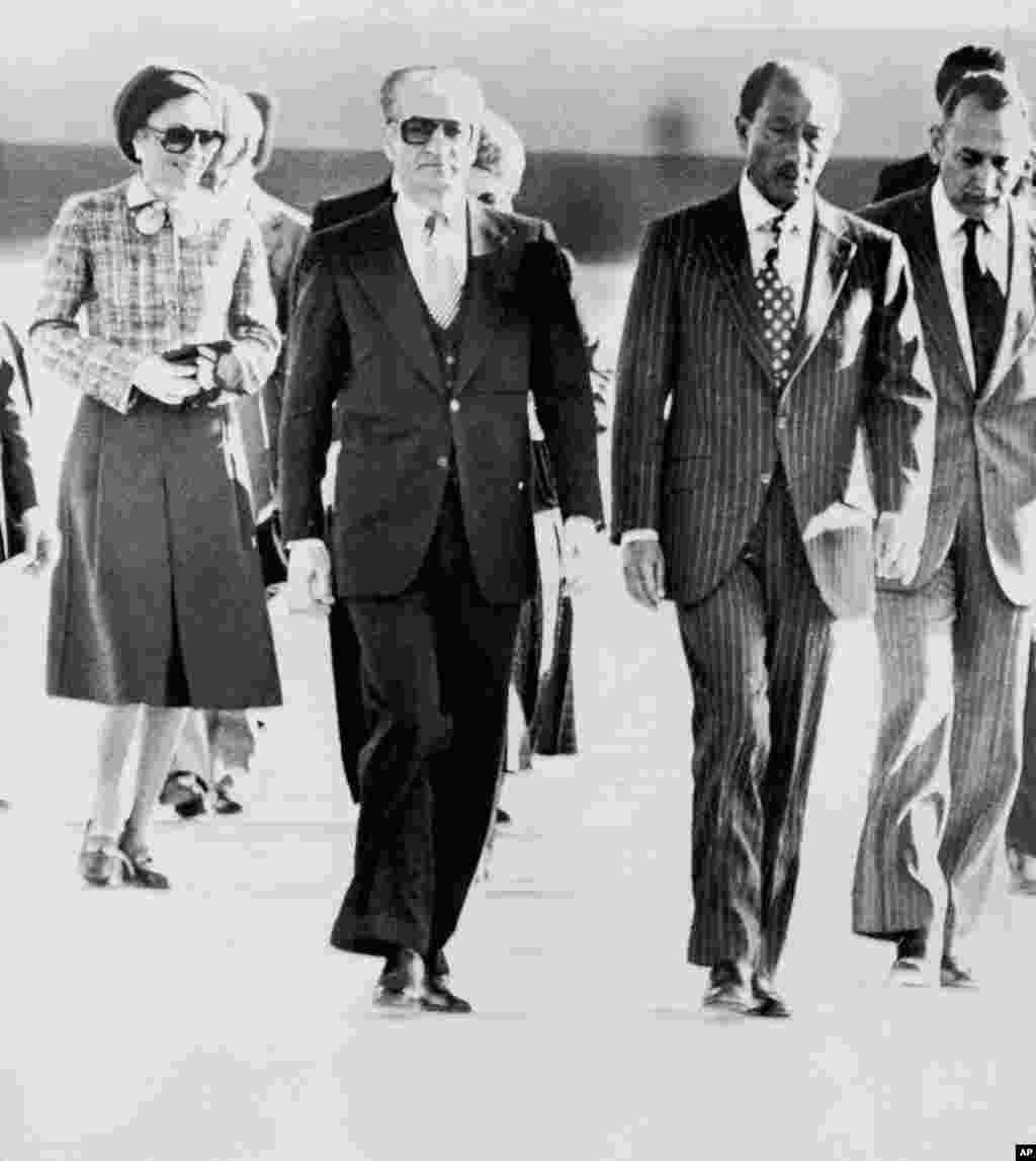 Король Ирана шах Мохаммед Реза Пахлави покидает страну 16 января 1979 года. Сначала королевская пара переехала в Египет. На фотографии шаха и его жену, императрицу Фарах, встречает президент Египта Анвар Садат (второй справа). Студентов в Тегеране разозлило то, что президент США Джимми Картер разрешил шаху приехать в Нью-Йорк для лечения от рака. Шах бежал из страны в разгар революции. До этого верная ему гвардия жестоко подавляла антиправительственные выступления в различных городах Ирана.&nbsp;&nbsp;