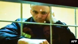 Liderul rus de opoziție, Alexei Navalnîi, a fost mutat din închisoarea în care se afla și dus ăntr-un loc necunoscut. Foto: Alexei Navalnîi apare pe un ecran în timpul unei audieri la un tribunal din Moscova. 