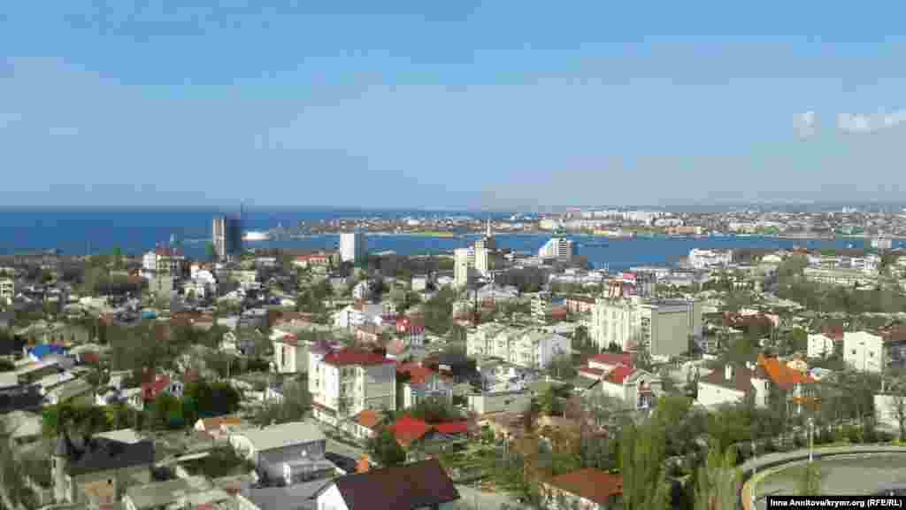 Панорама весеннего Севастополя. Этот вид мало изменился спустя три года. Но есть одна особенность – здание, которого не стало с приходом в город российских властей. Снос серой недостроенной шестнадцатиэтажки (в левой части кадра) севастопольцы запомнили надолго. Для взрывных работ были приглашены российские специалисты. Справились не сразу: прогремел первый взрыв и здание наклонилось, прогремел второй – часть дома устояла, остальное разбирали вручную. Образовавшаяся свалка на месте бывшей стройплощадки долго красовалась в центре города, рядом с историческим памятником. Причина сноса – нарушение градостроительных норм. Здание нельзя, свалку можно Севастополь, 17 апреля 2014 года, площадь Восставших