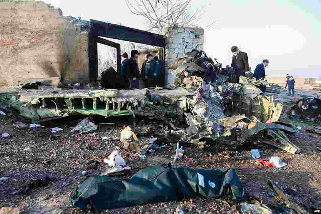 Njerëzit qëndrojnë pranë rrënojave të avionit të rrëzuar ukraninas në Iran, që kishte në bord 176 pasagjerë. 